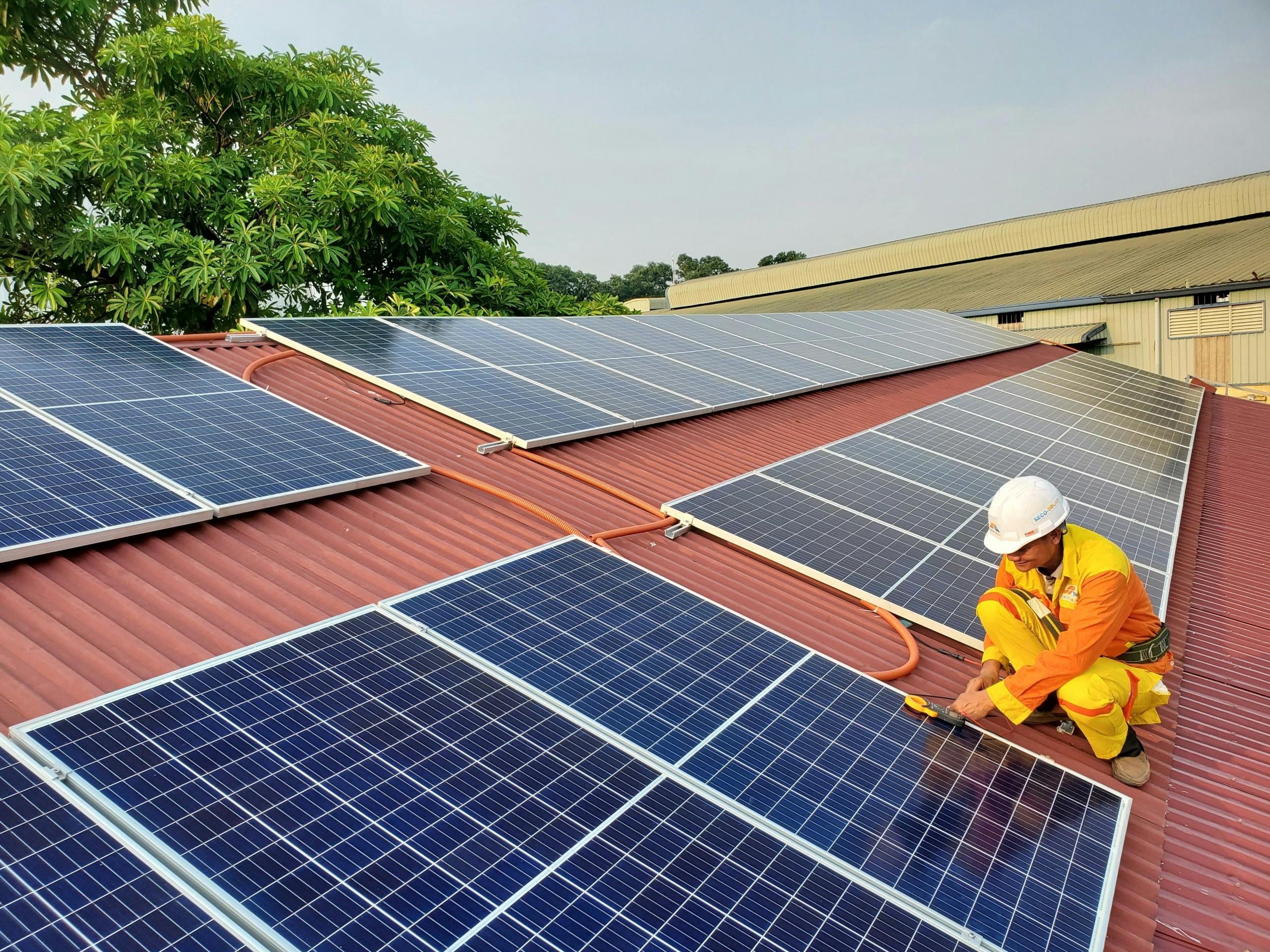 man installing solar panels on a metal roof